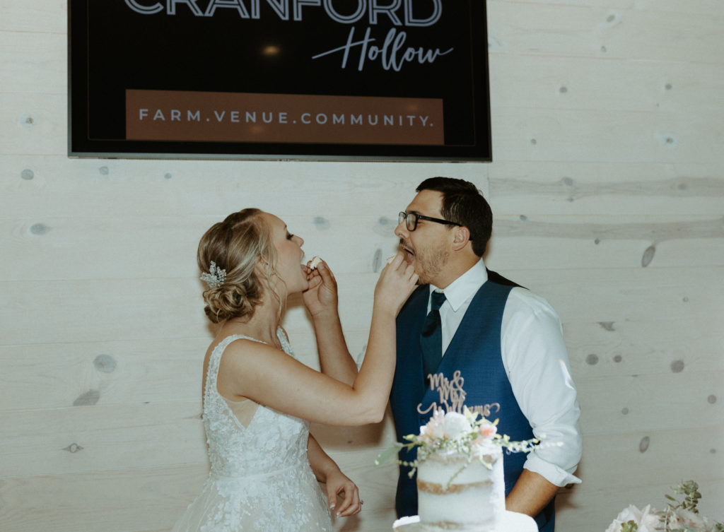 Cody and Amanda feeding eachother cake during their reception on their wedding day at Cranford Hollow.