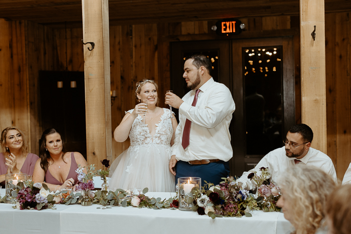 Juan and Rachel during champagne toasts on their wedding day inside the barn at firefly lane. 