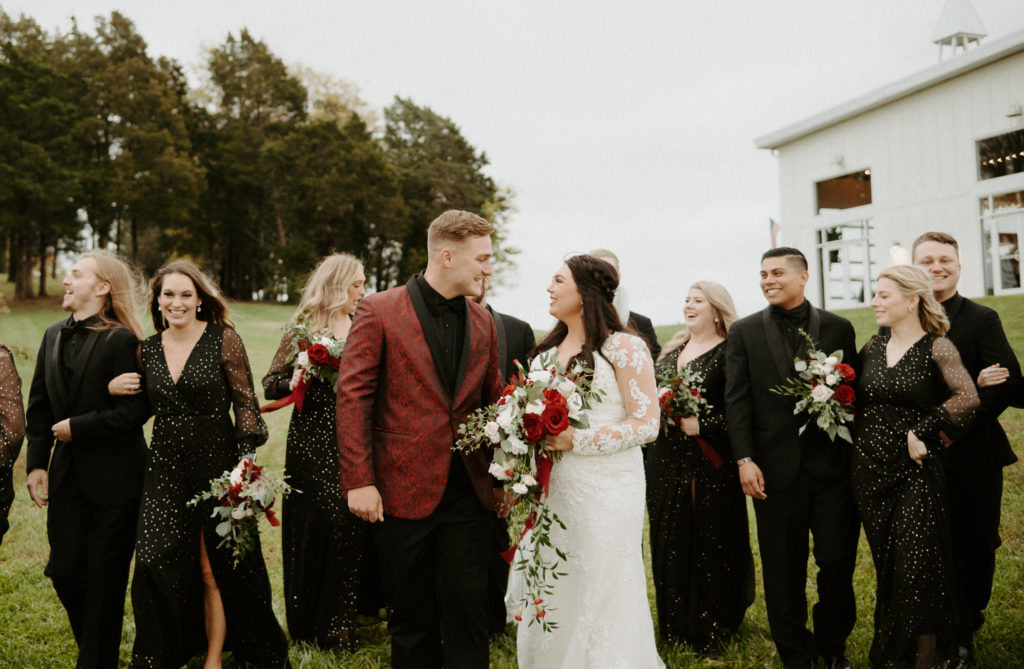 Shelby and Jacob smiling at each-other as they walk down the hill with their bridal party after their ceremony at The Ruby Cora. 