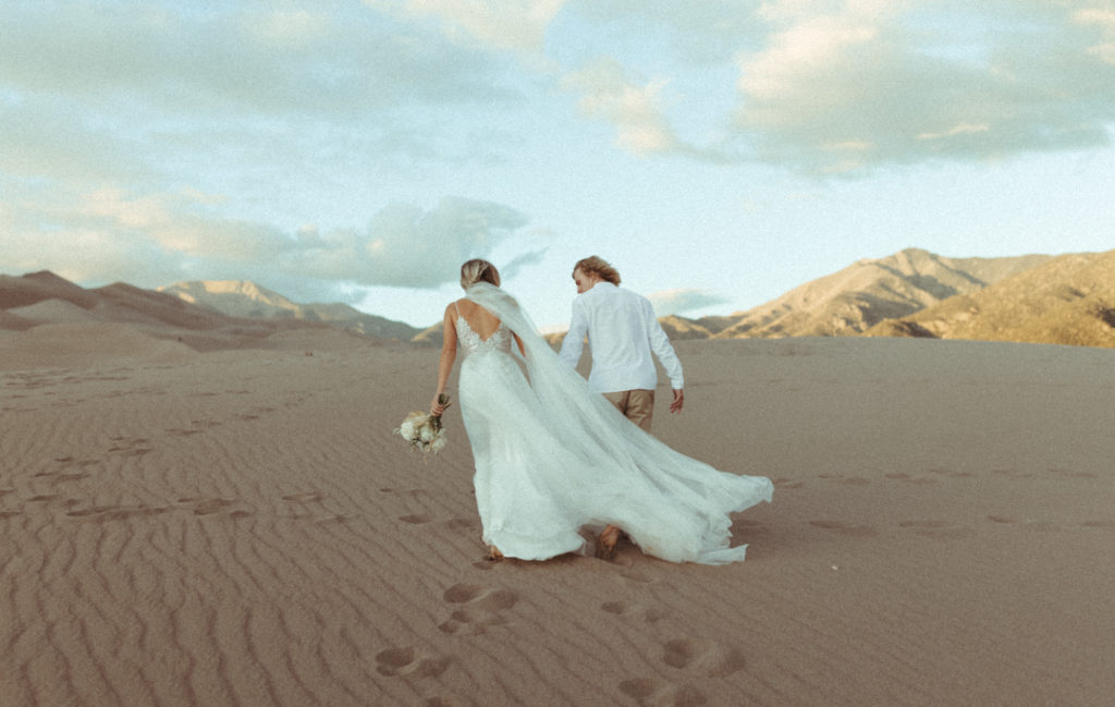 Bride and groom walking away during their sandy Colorado Elopement at The Great Sand Dunes National Park. 