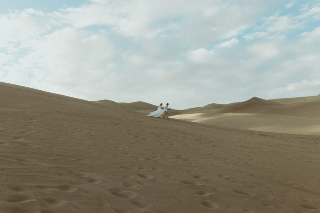 Wide and shot of the couple running through the sand during their Colorado Elopement. 