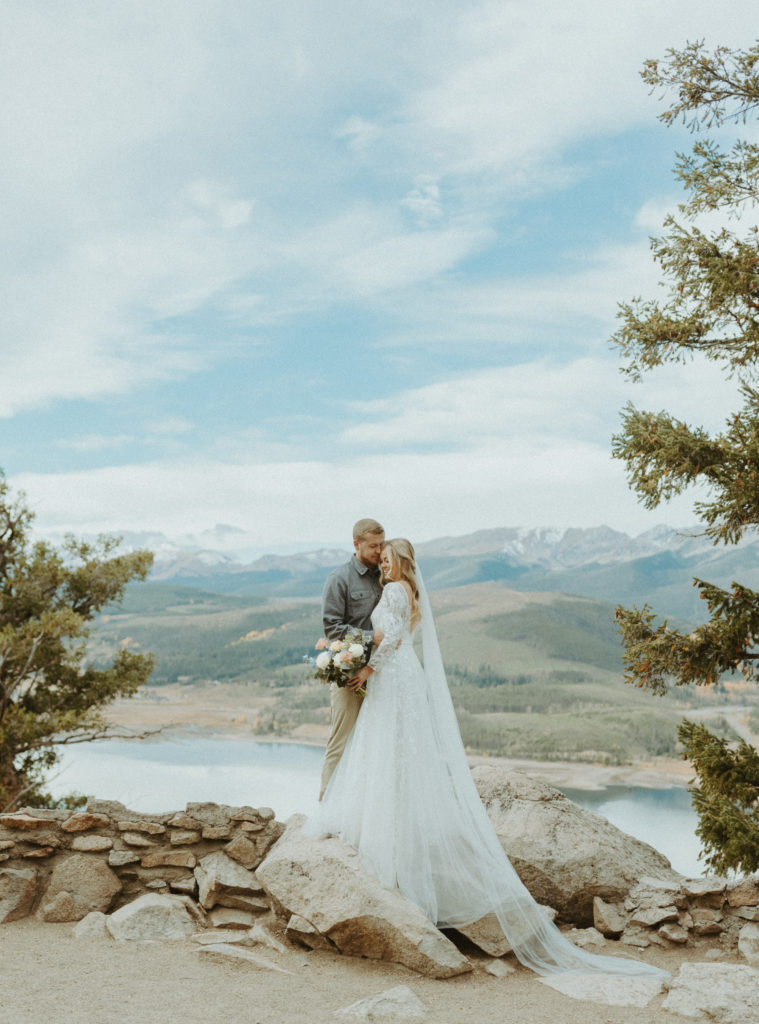 Bride and groom holding eachother on the Sapphire Point overlook in Frisco, Colorado. 