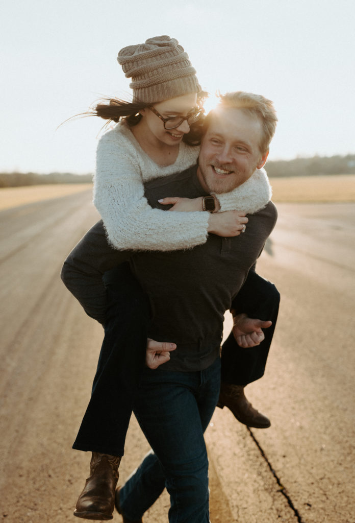 Sean giving Mariah a glowy piggyback ride during their engagement session at Cornelia Fort Airport in Nashville, Tennessee. 