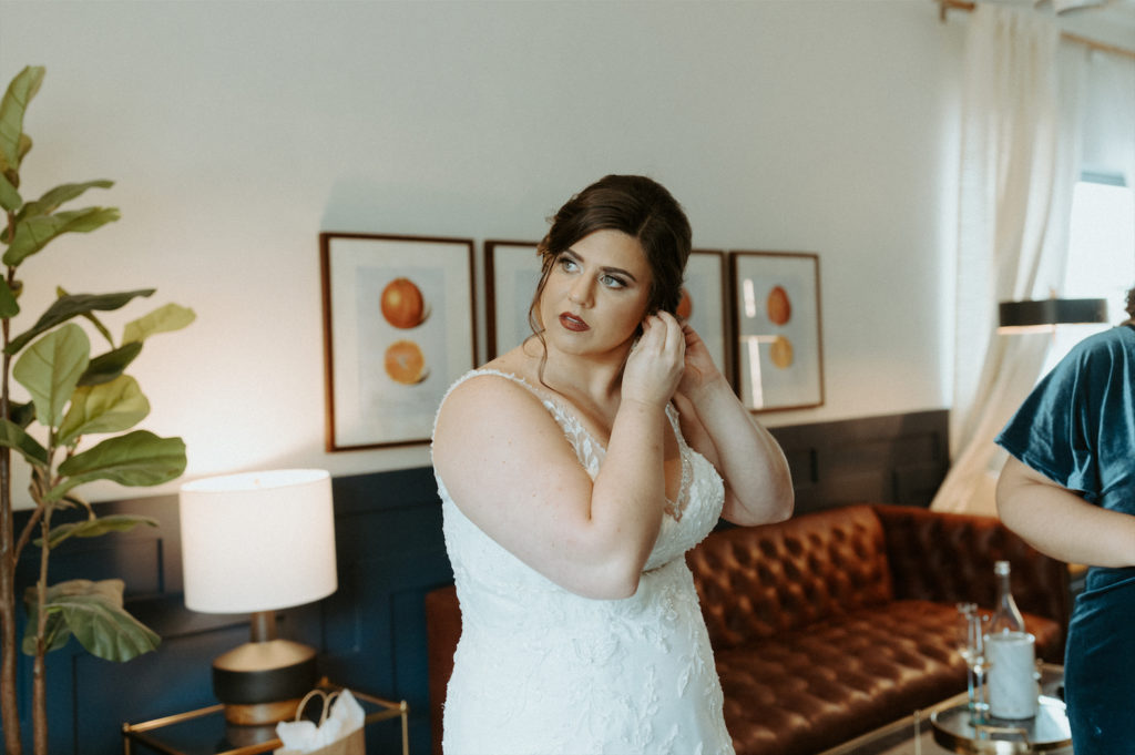 Marissa putting in her earrings during her wedding day at The Clementine