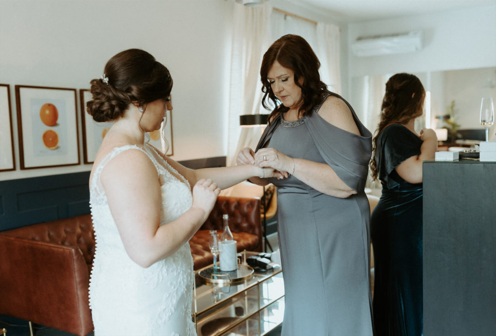 Marissa's mom helping her put on jewelry during her wedding at Clementine