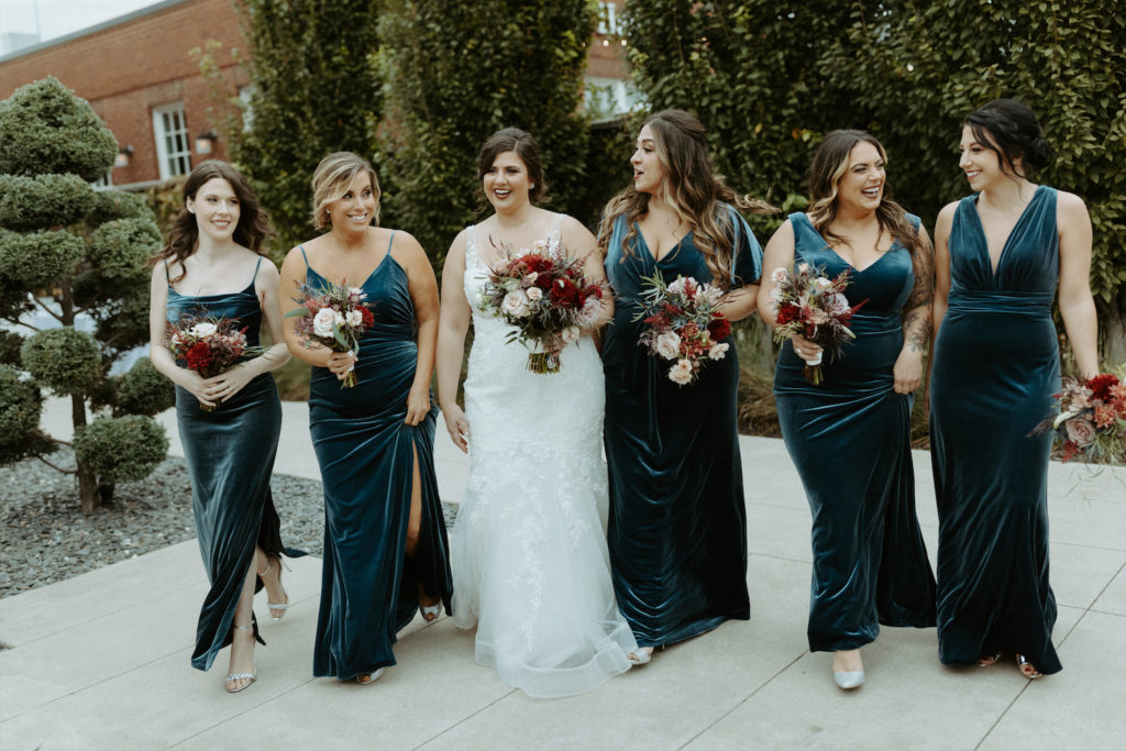 Marissa and her bridesmaids walking in the courtyard during her fall wedding at Clementine Hall.