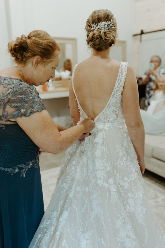 Amanda's mother buttoning the back of her wedding dress on her wedding day.