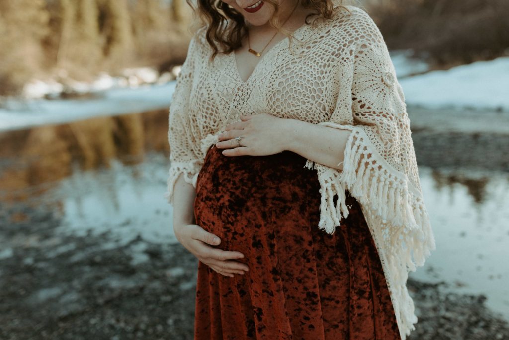 A woman holding her belly wearing a boho maternity dress.