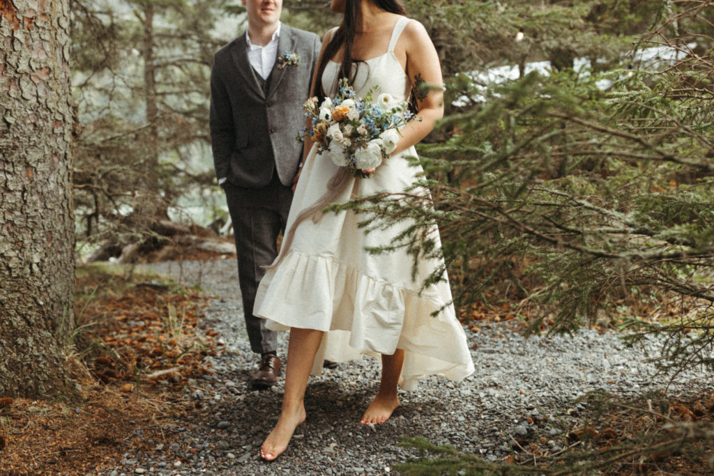 Bride holding her wedding bouquet walking through the woods