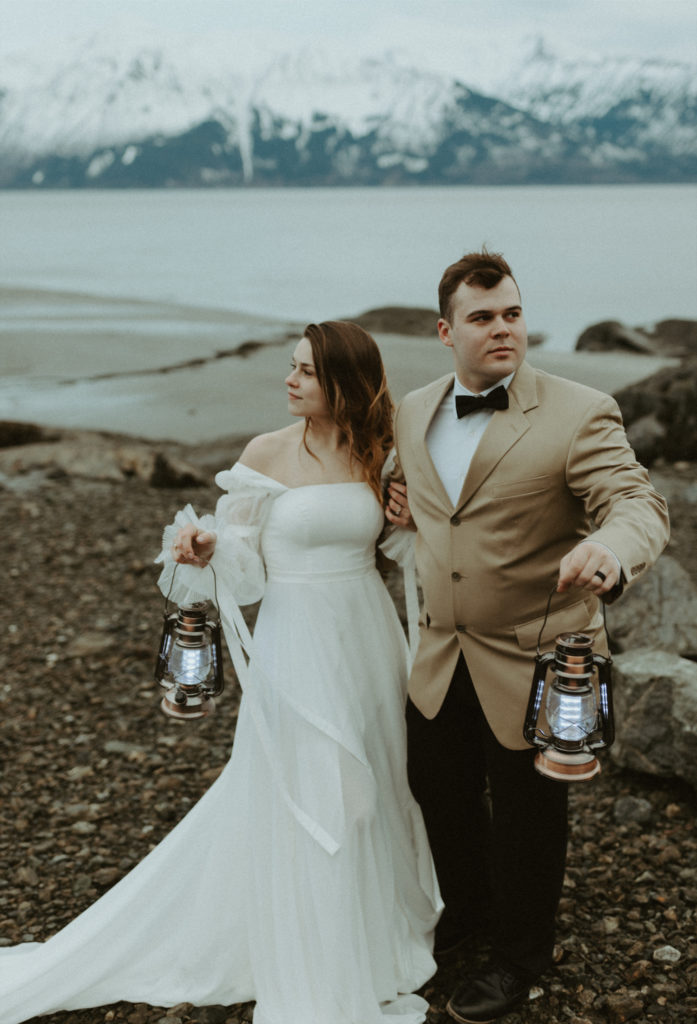 Alaska couple holding lanterns during their beach elopement
