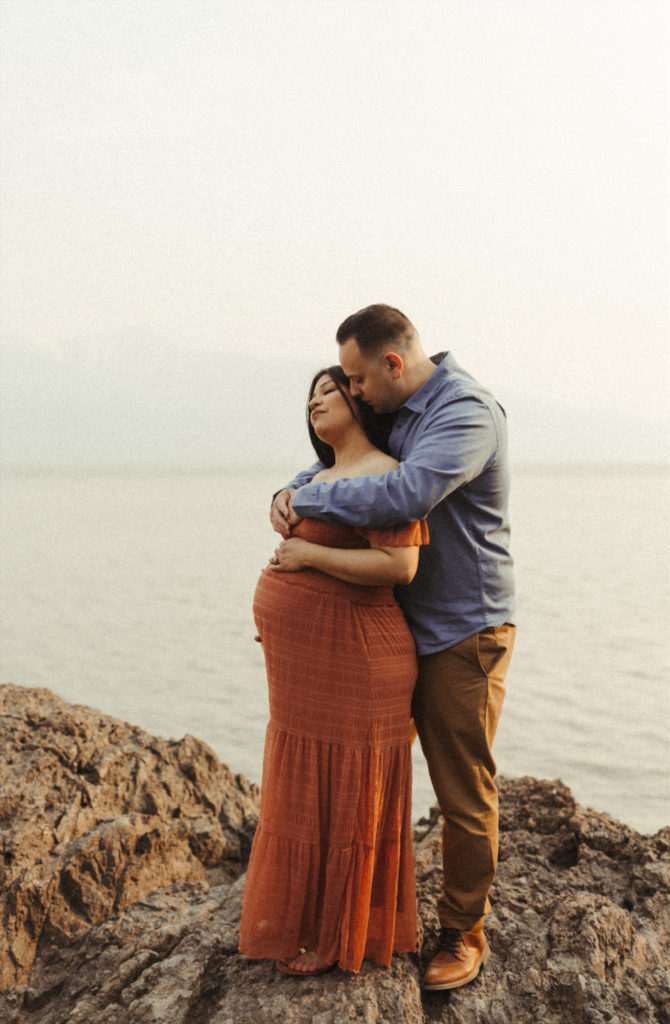 Soon to be parents looking out over the ocean during their maternity photo session