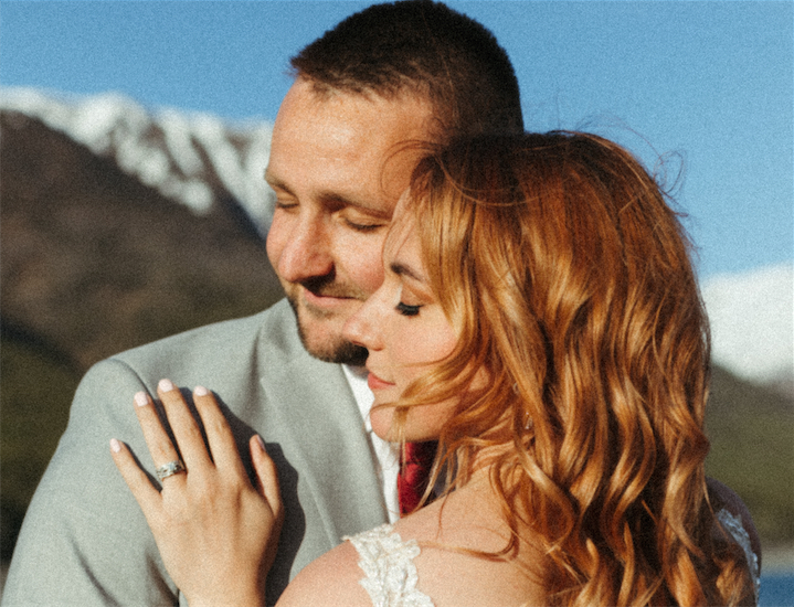 Couple cheek to check looking out to the mountains during their wedding like photo session