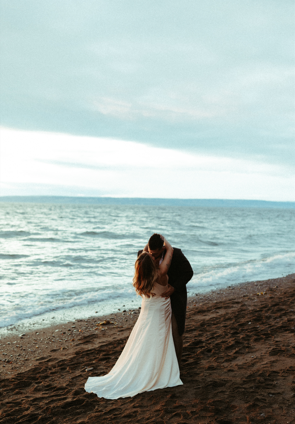 Bride and groom standing next to the ocean in Homer, Alaska