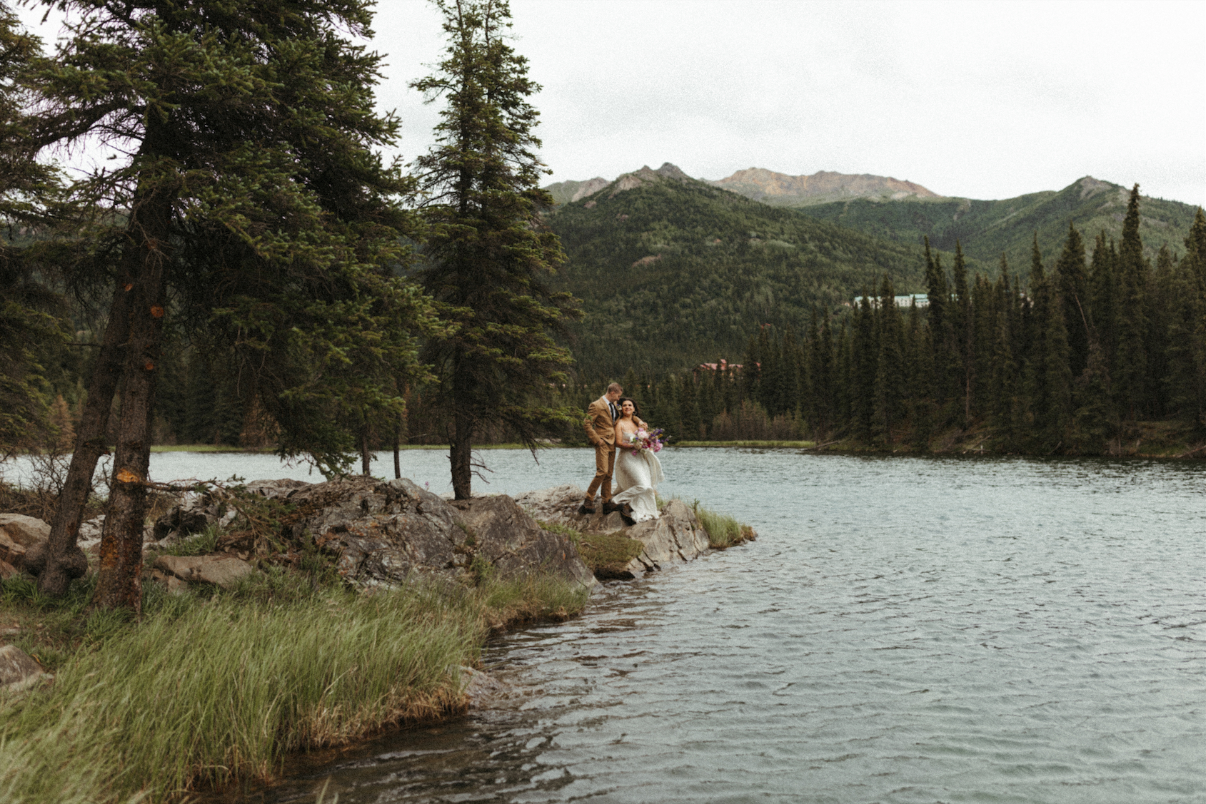 Dreamy wide view of a couple standing on a rock during their elopement 