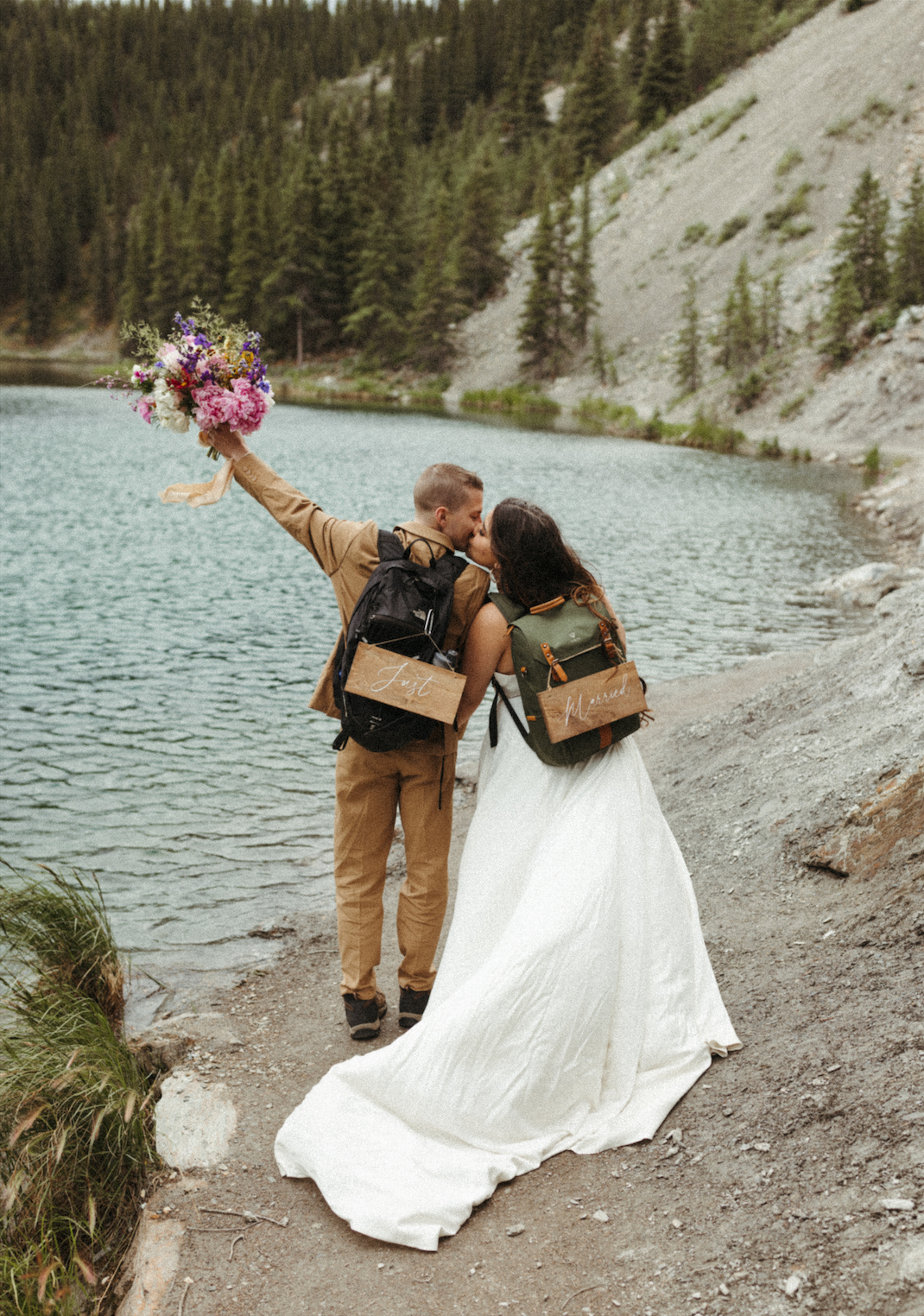 Couple wearing backpacks and kissing during their elopement 