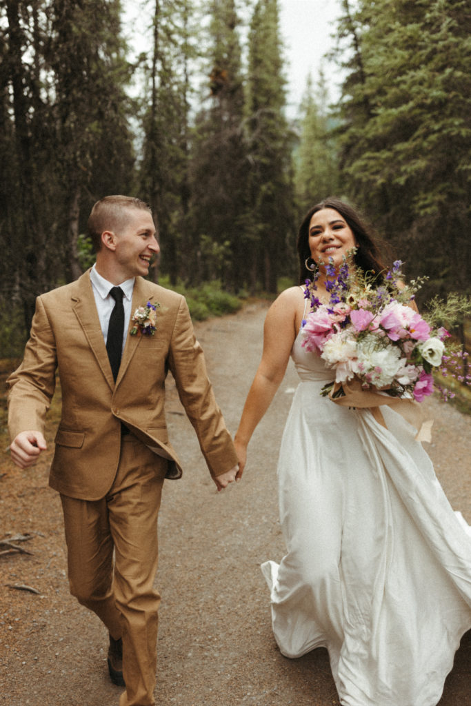 Couple running through the woods during their Denali National park elopement 