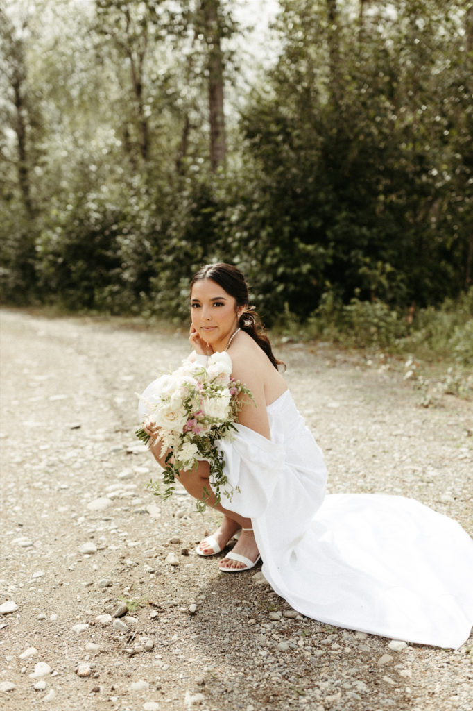 Woman posing for portraits after having her hair and makeup done for an outdoor wedding in Alaska.