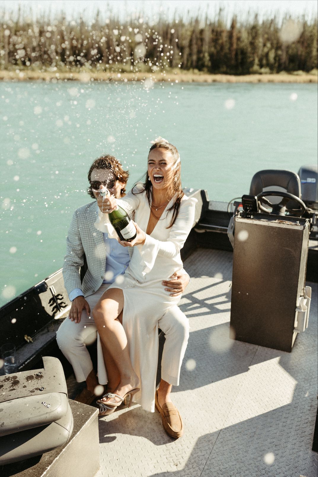 Couple popping champagne during boat wedding photos in Kenai Alaska