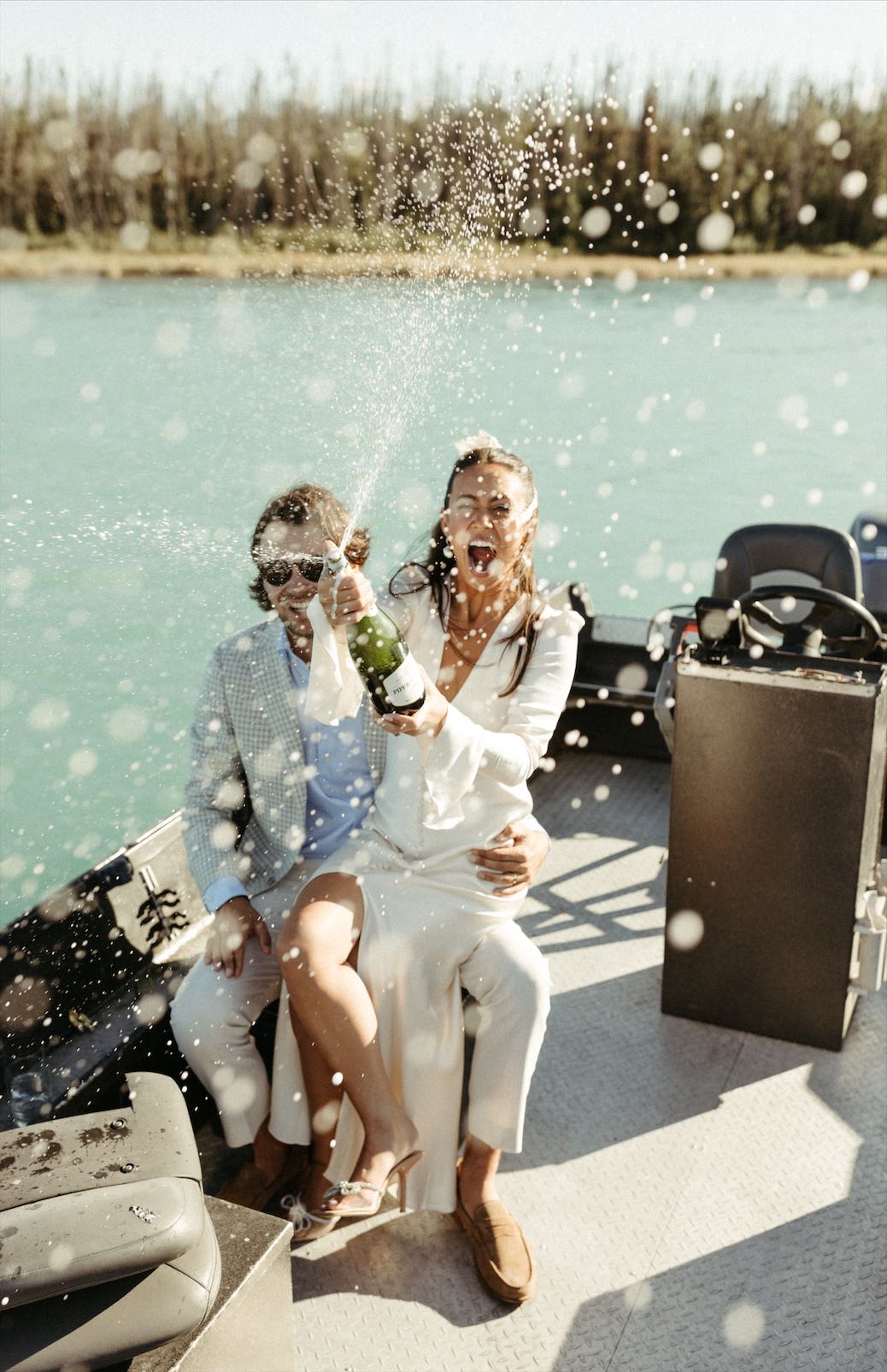 Couple popping champagne on their boat for their wedding photos