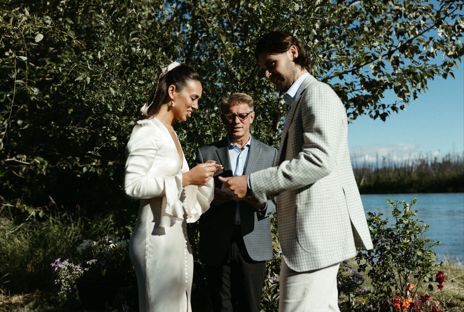Woman putting the ring on her husbands hand during their wedding ceremony 