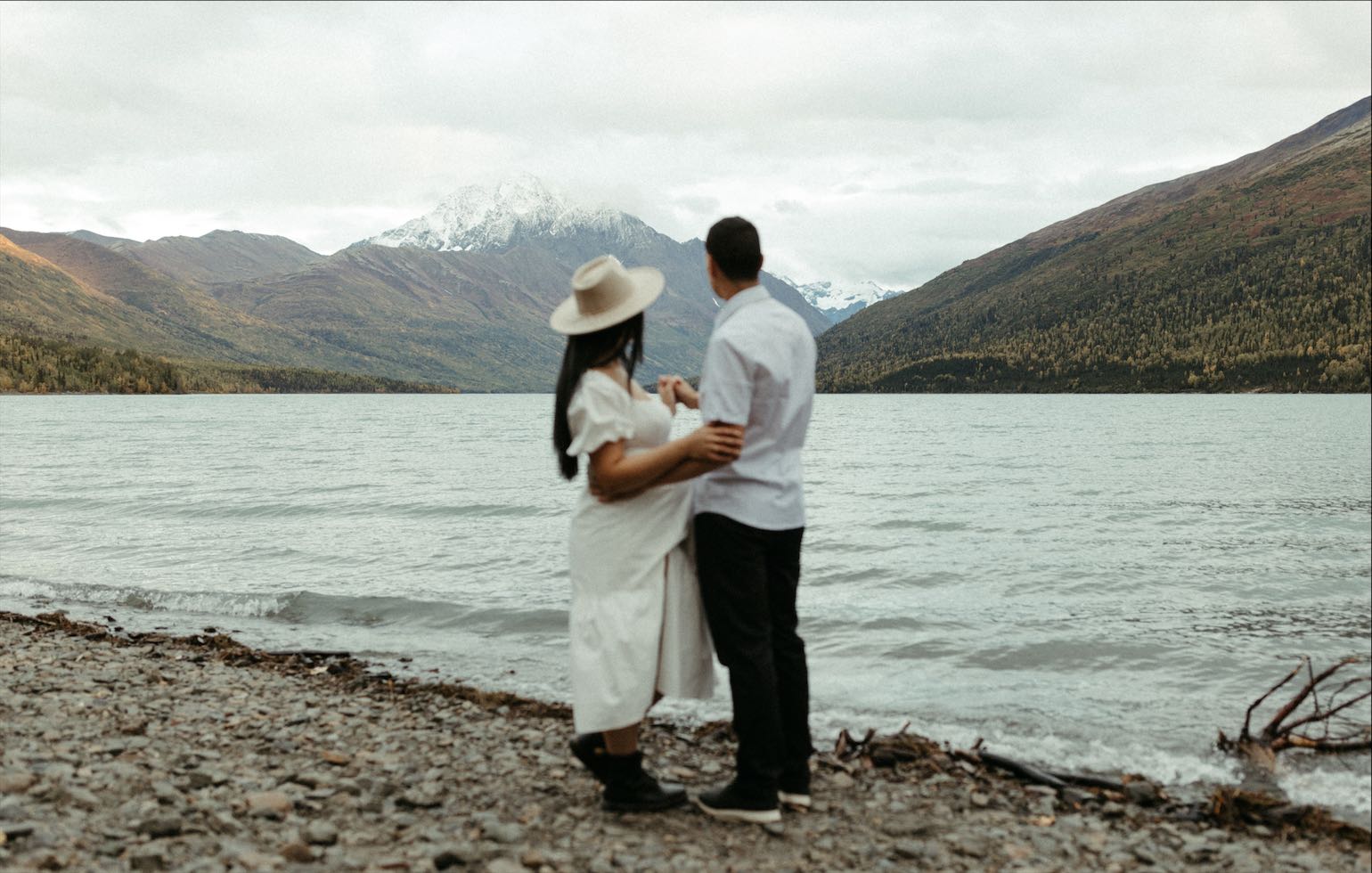 Couple taking in mountain views during the photo session at Eklutna Lake in Chugiak Alaska