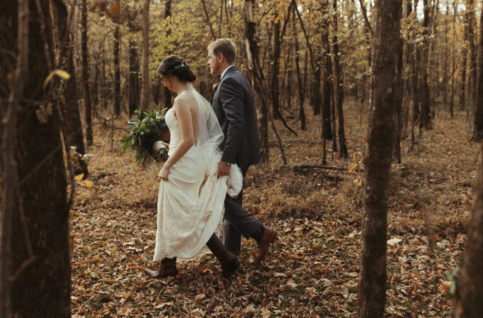 Couple walking through the woods during their fall wedding