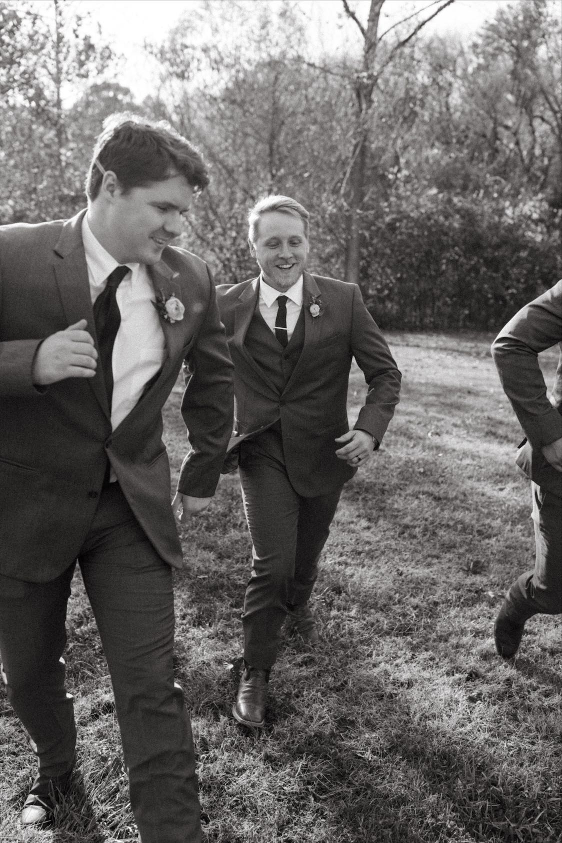 Groom and groomsmen running during bridal party photos at Double Creek Farm