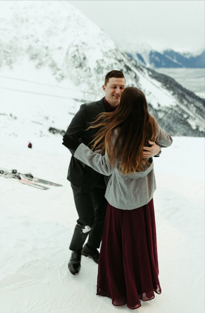 Couple embracing after a snowy proposal at Alyeska Ski Resort in Girdwood, Alaska 