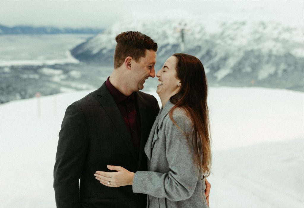 Couple taking in the mountain views after their winter proposal shot Michelle Johns an Alaska wedding photographer