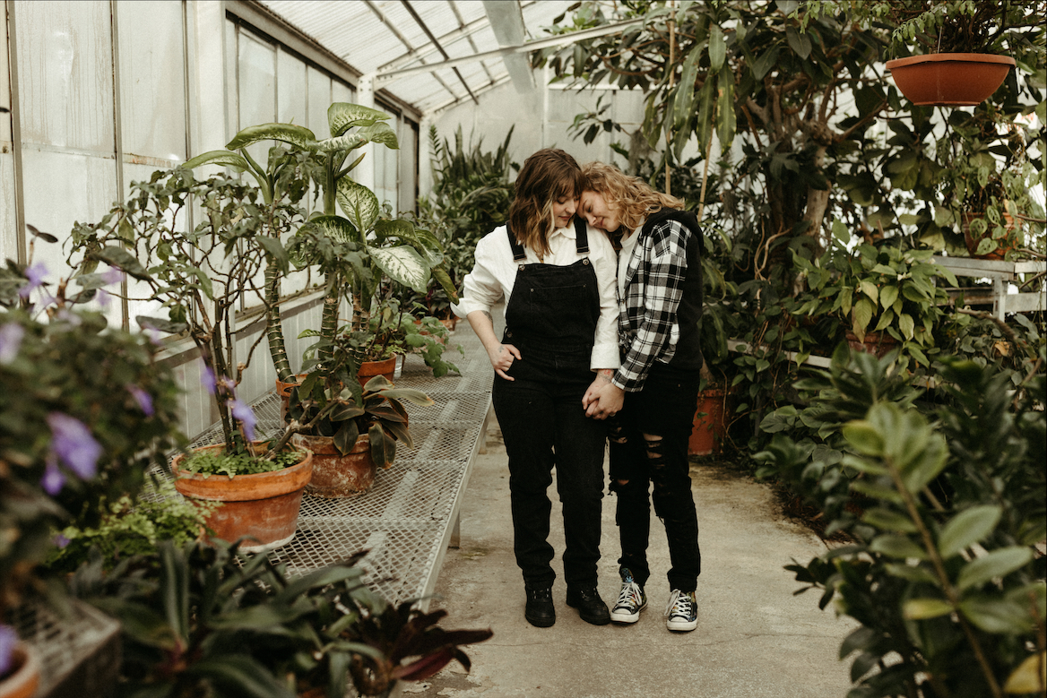 Couple snuggled close during their greenhouse engagement session in Anchorage, Alaska