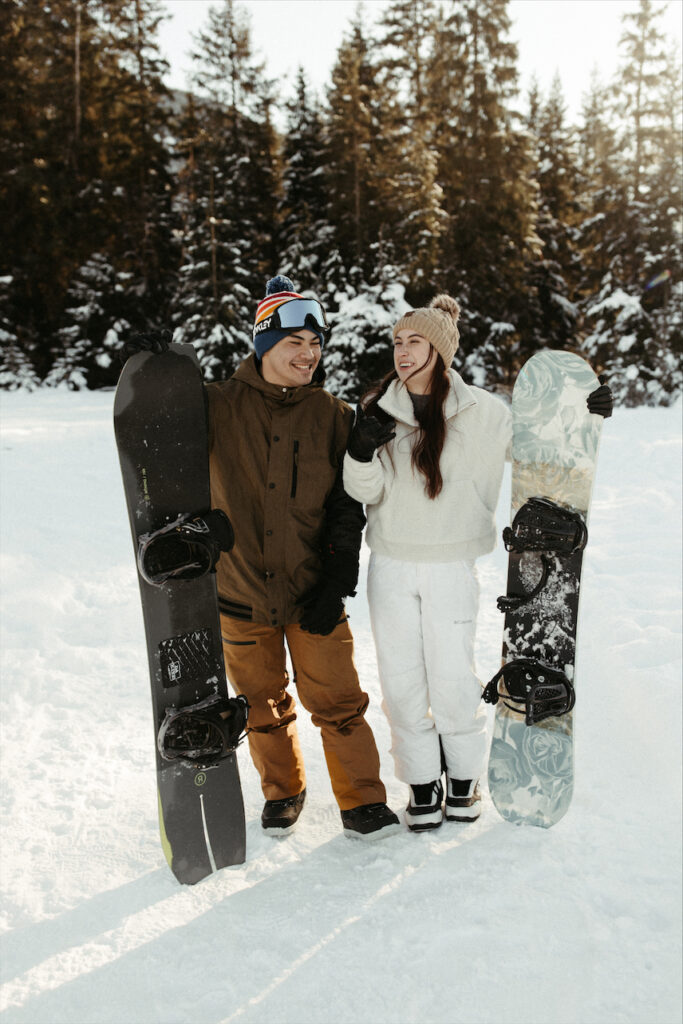 Couple holding their snowboards during their engagement session 