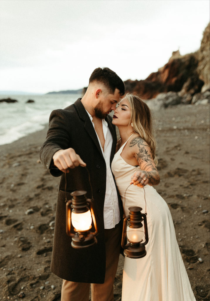 Couple holding lanterns on the beach during their elopement 