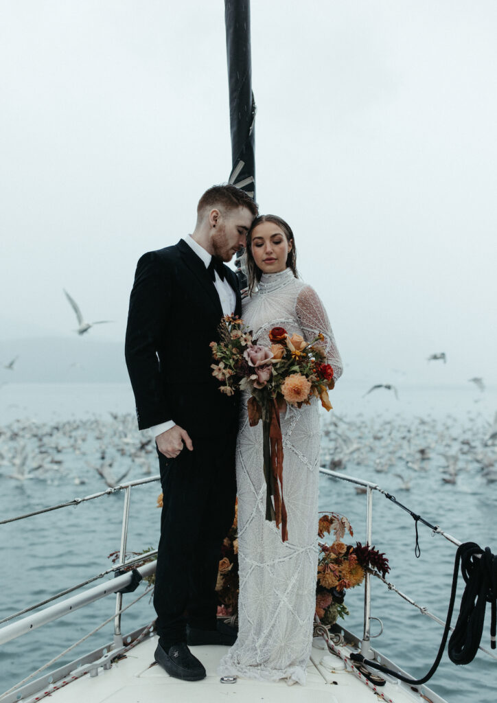 Couple snuggled together holding onto a bouquet of flowers during their elopement in Seward, Alaska. 