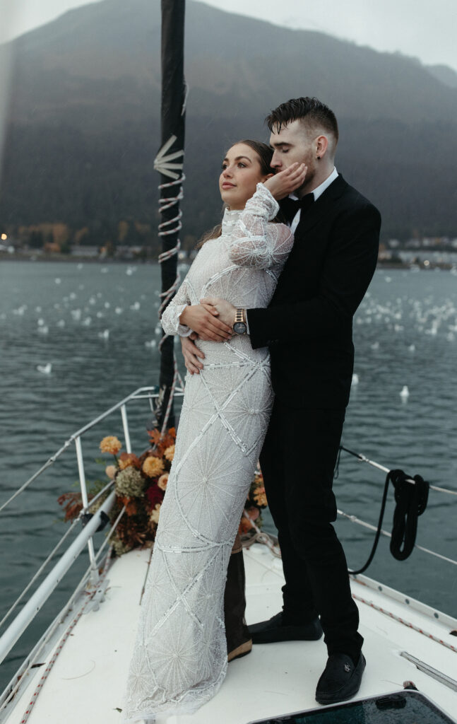 Couple snuggled close at the front of the boat during their adventure elopement in Seward, Alaska.