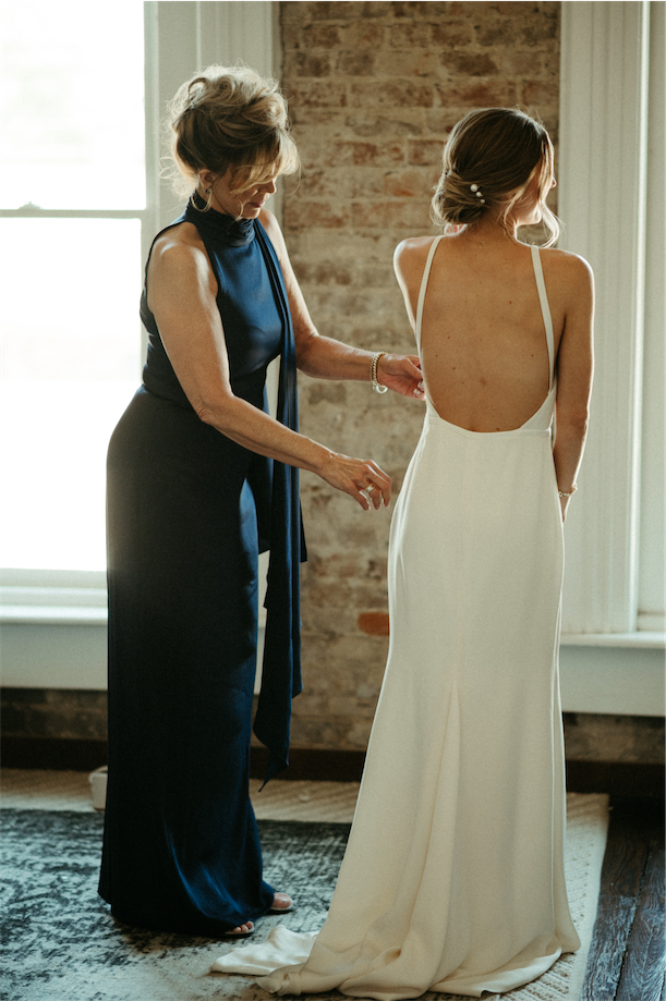 Mom buttoning her daughters dress while getting ready at one of the best wedding venues in Nashville