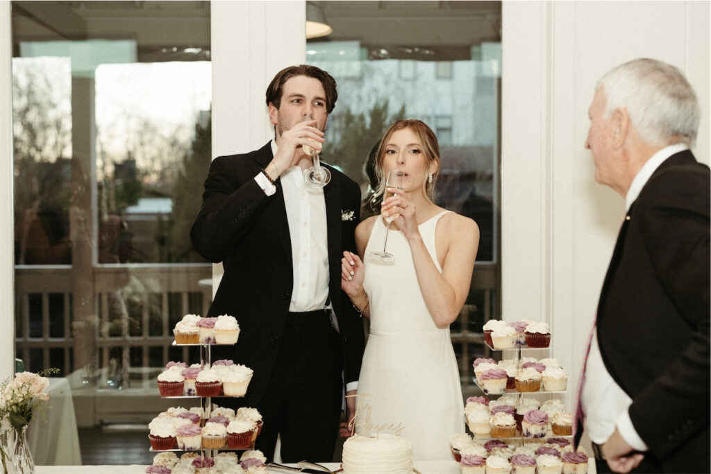 Couple sipping on champagne after cutting their wedding cake