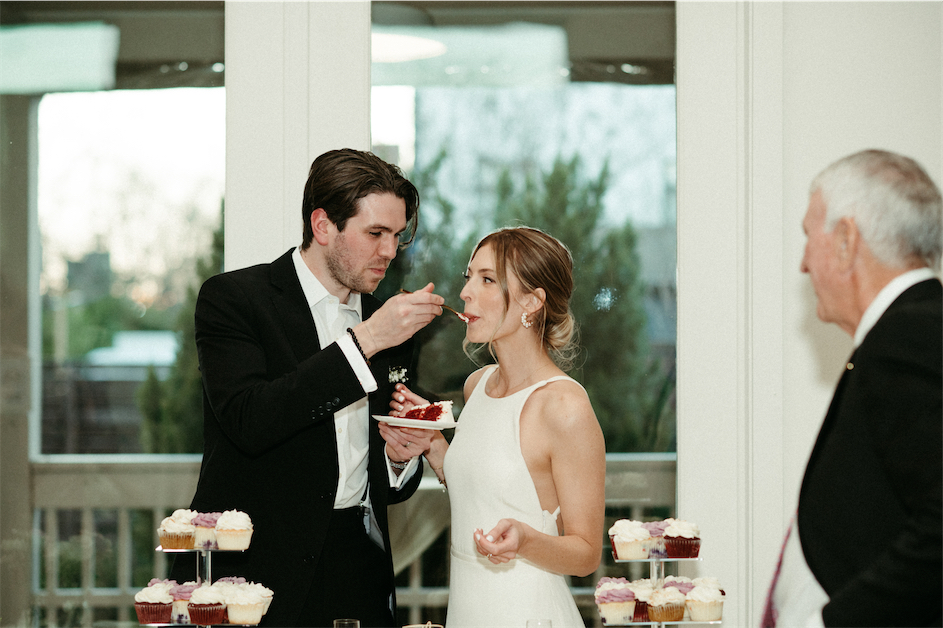 Groom feeding his bride a bite of wedding cake during their spring wedding at The Cordelle