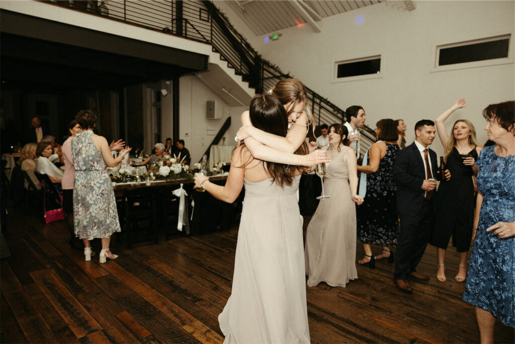 Bride jumping into the arms of one of her bridesmaids during her wedding at The Cordelle