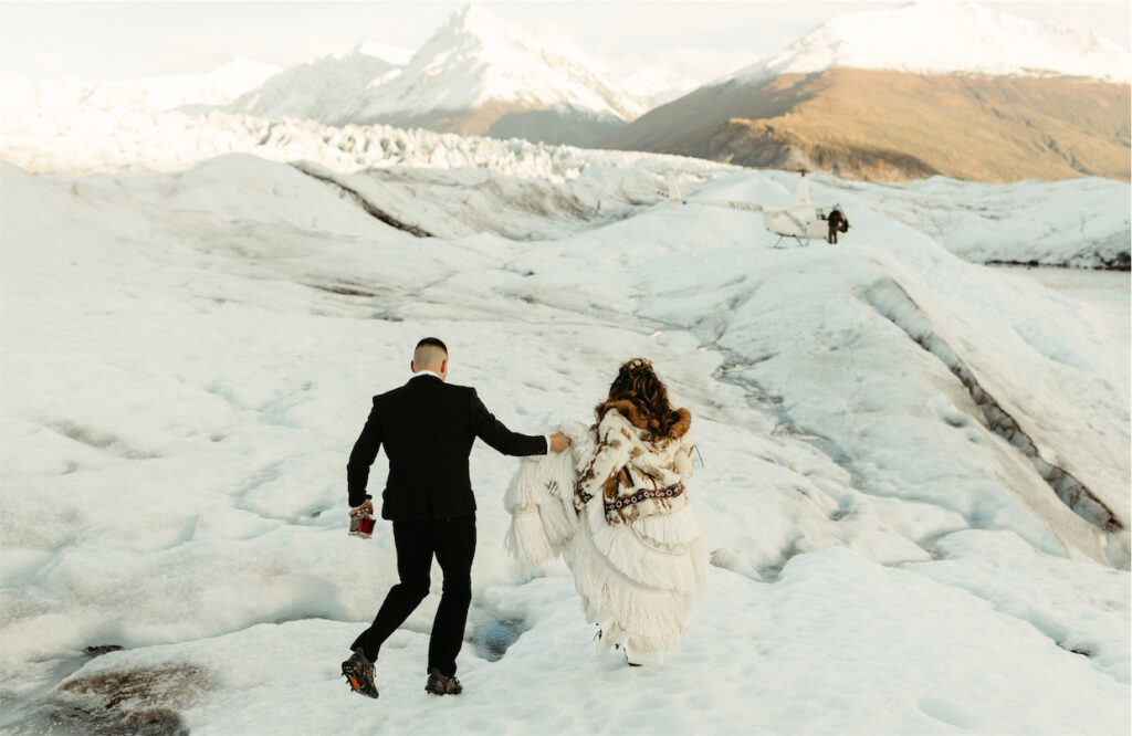 Couple walking toward their helicopter during their glacier elopement