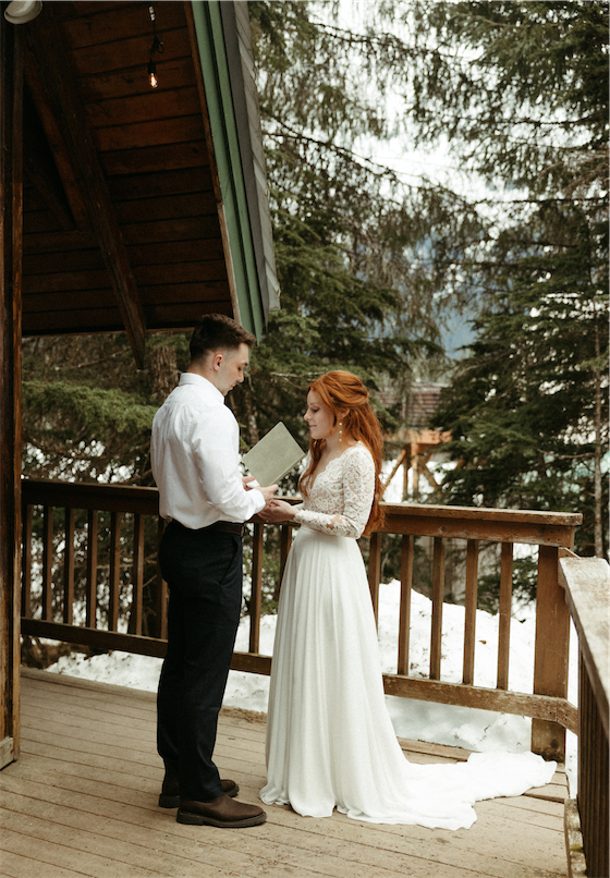 Woman reading her elopement vows outside of an a frame cabin in Girdwood, Alaska