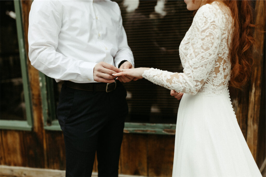 Man placing ring on woman's finger during an elopement ceremony in Girdwood, Alaska