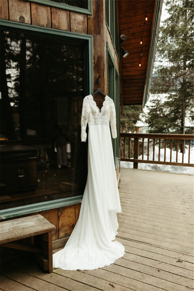 Dress hanging outside of an a frame cabin during a winter elopement
