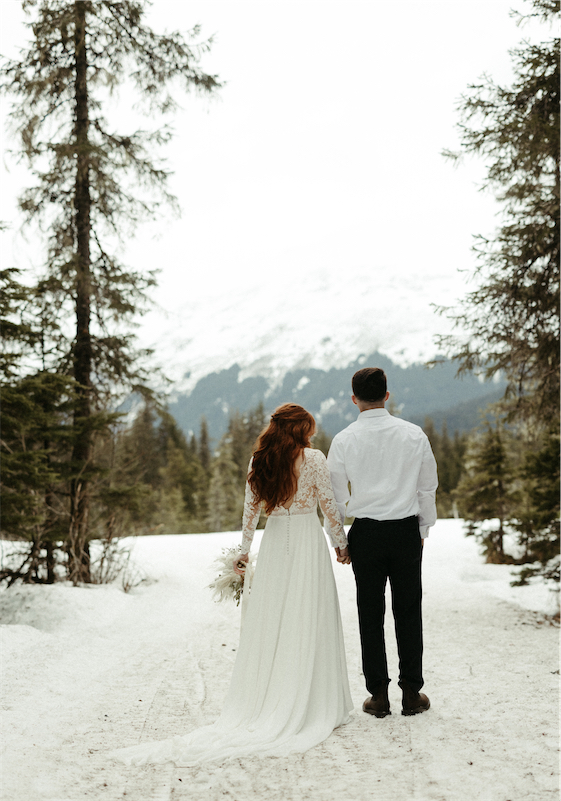 Couple standing in the snow in wedding attire