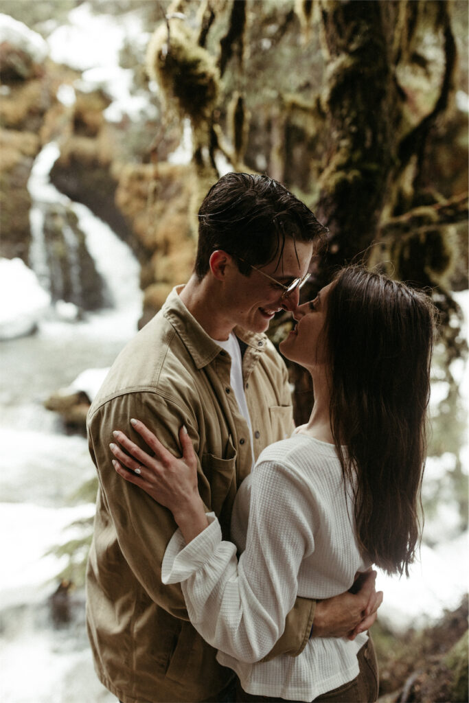 Couple almost kissing next to virgin creek falls during their spring engagement session 