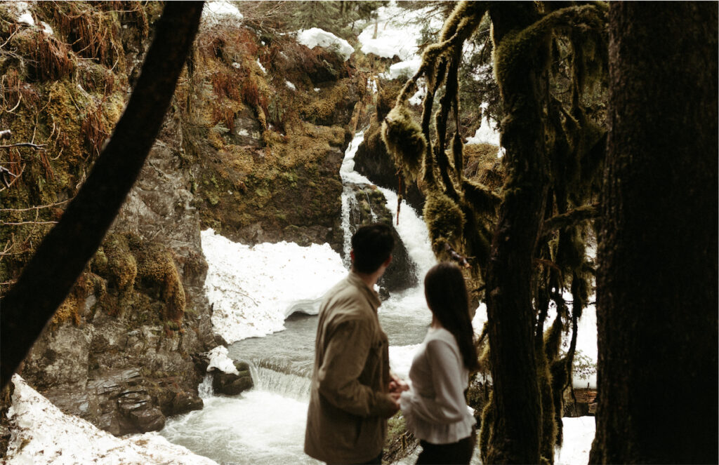 Couple looking at a waterfall during their time in Alaska