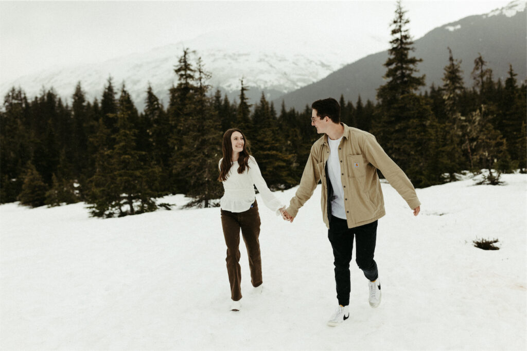 Couple running while holding hands in Girdwood, Alaska