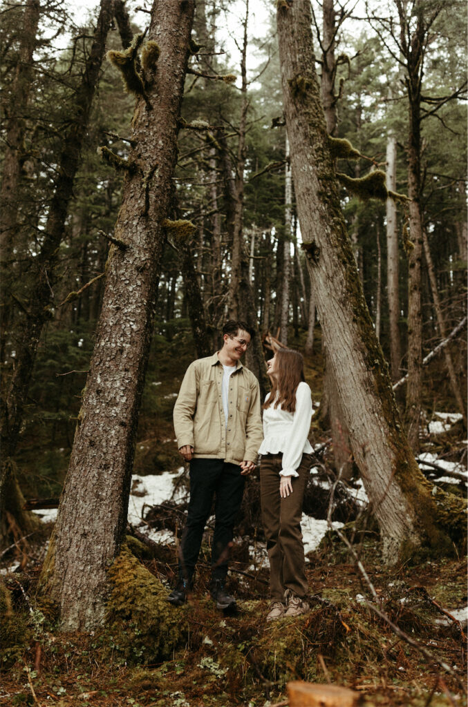 Couple standing amongst the trees during their engagement session in Alaska 