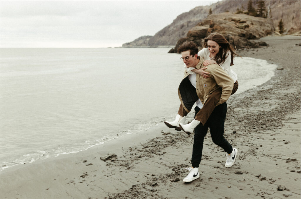 Couple running along a beach during their Girdwood engagement session 