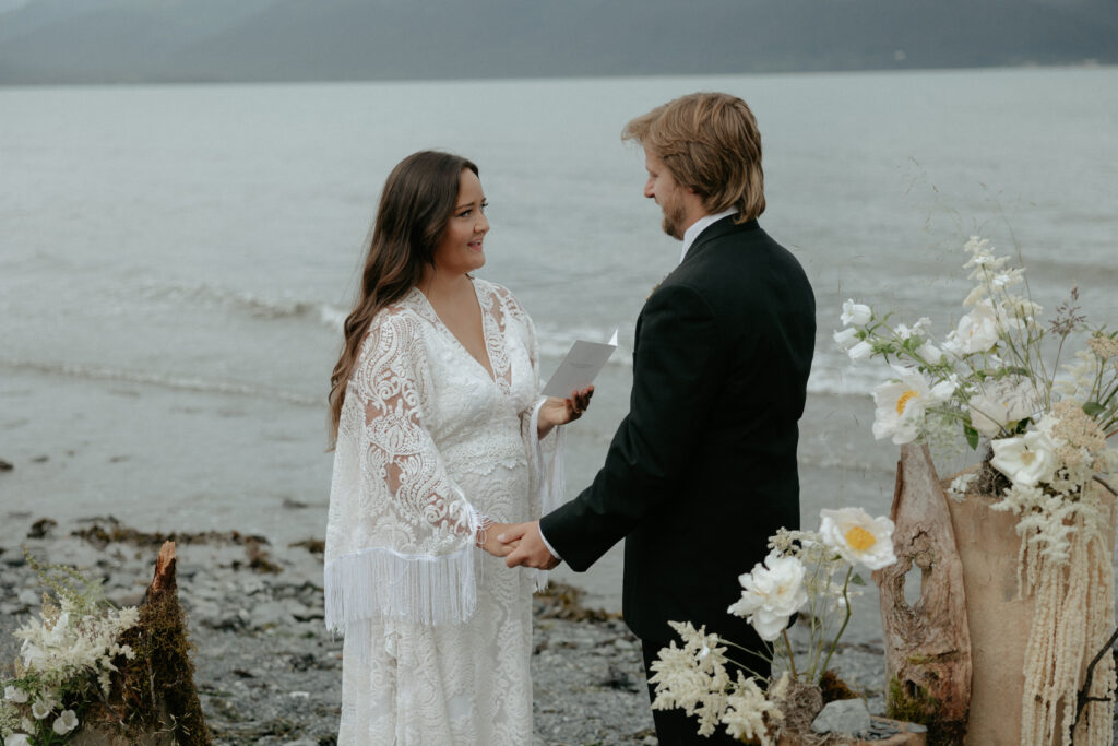 Woman holding a vow book while wearing a white dress. 