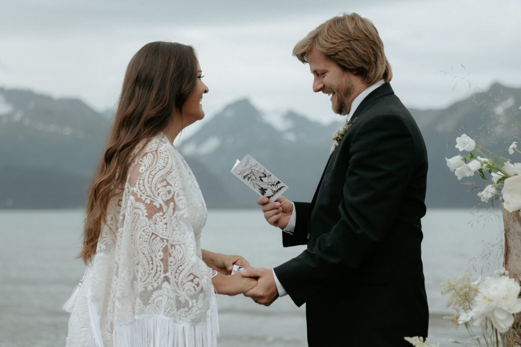 A man holding a white vow book and facing a woman wearing a white dress. 